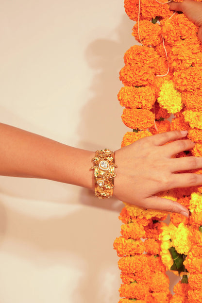 Luxury gold jewelry showcased on a hand with vibrant marigold garlands creating a festive ambiance
