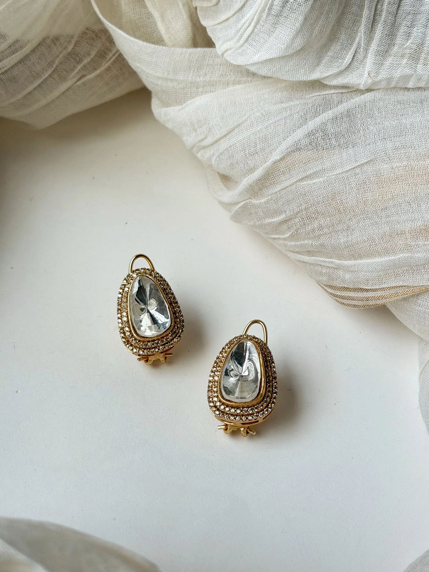 Premium gold and crystal jewelry set with layered necklace and teardrop earrings in flat lay styling
