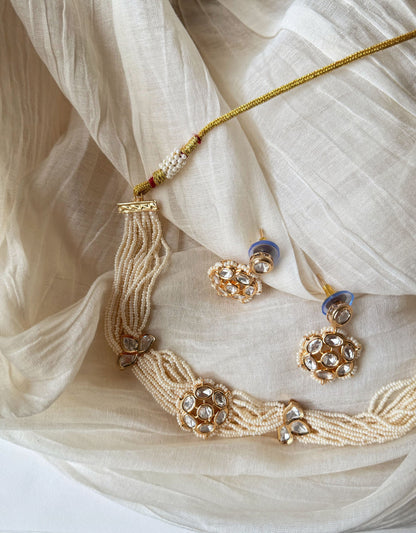 Traditional gold and kundan choker necklace with green stones in soft natural lighting
