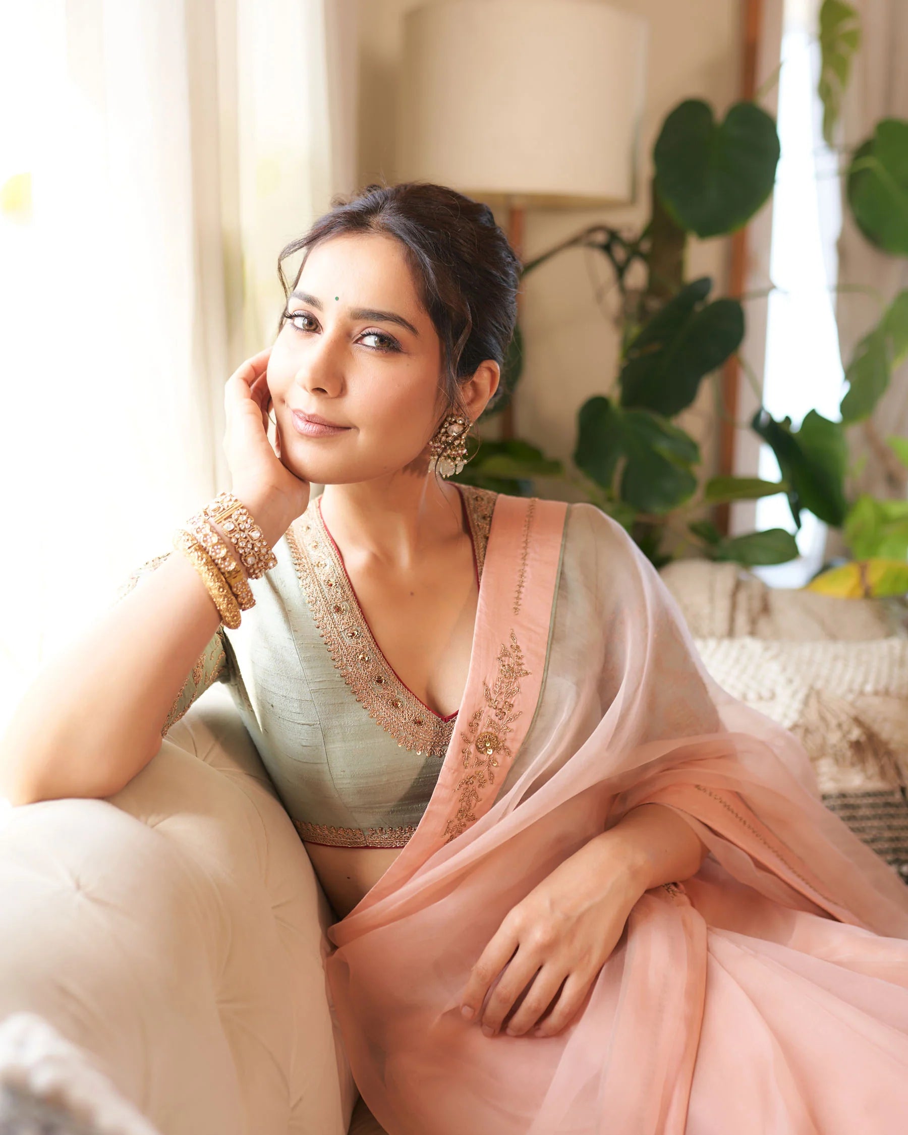 Fashion portrait highlighting Indian saree styling with gold bangles, earrings, and soft pastel tones
