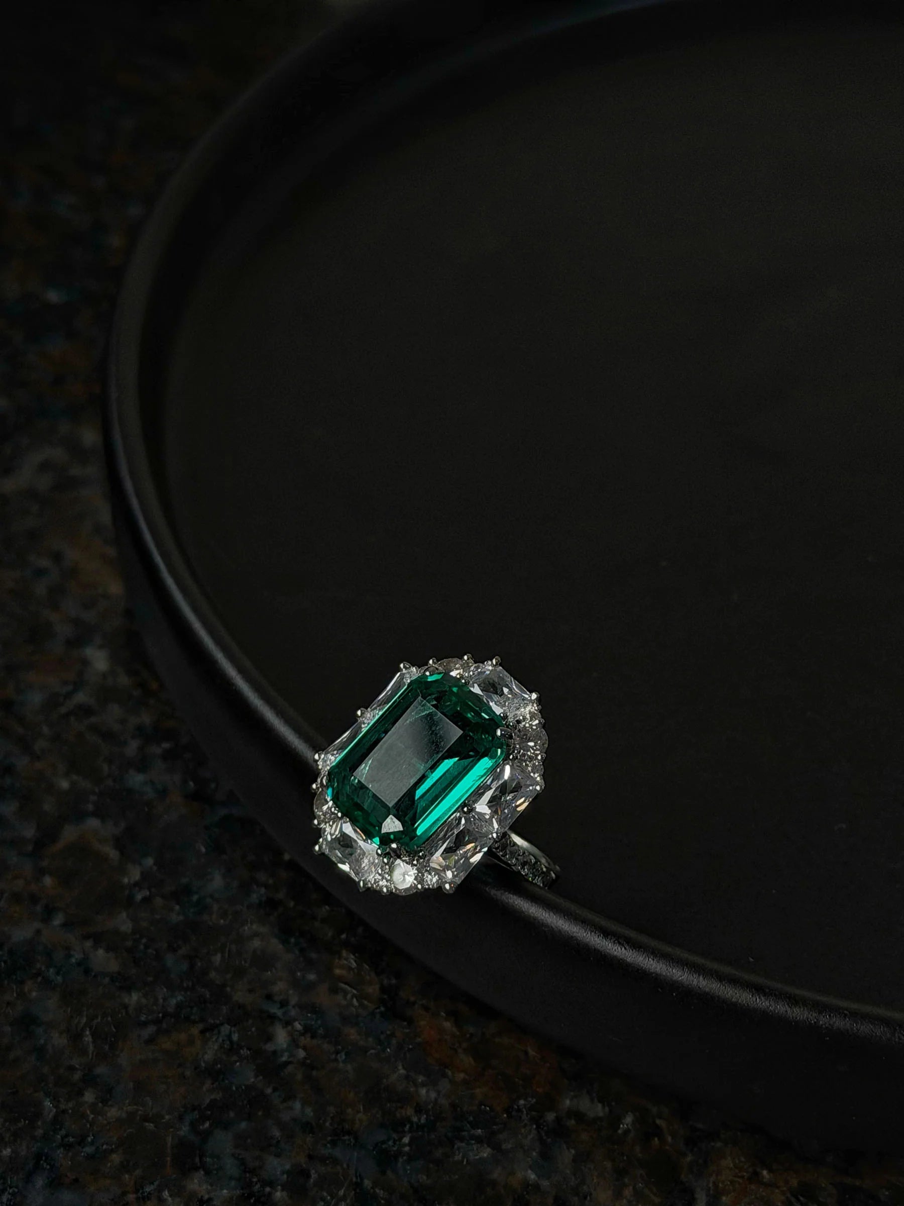 Elegant cocktail ring featuring large green emerald stone with sparkling diamond accents
