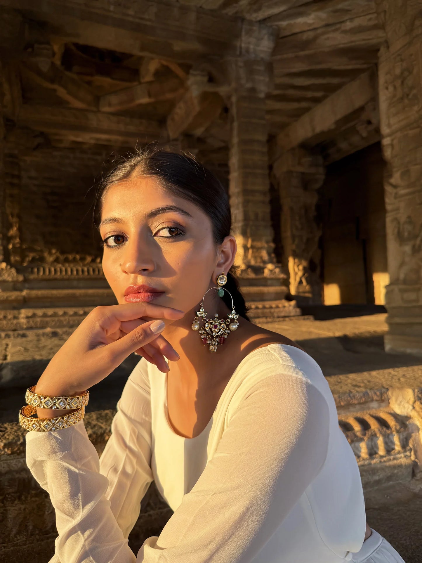 Fine jewelry styling shot featuring a woman in white attire with statement earrings, captured in an architectural landmark
