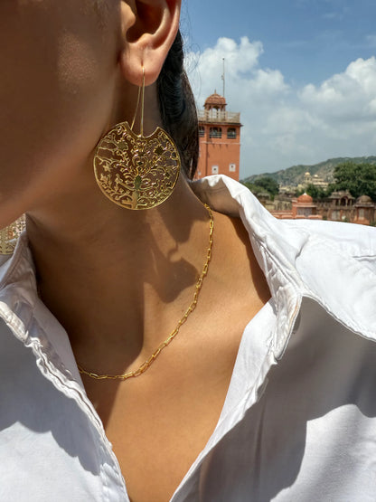 Elegant travel style image featuring gold earrings and historic building in soft daylight
