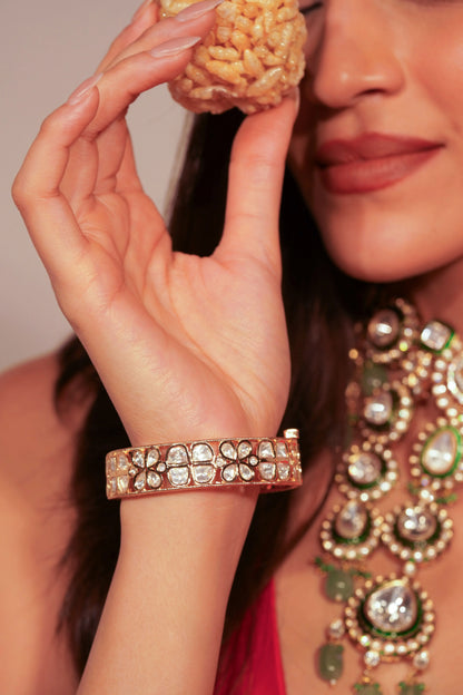 Fine accessory close-up highlighting a rigid bangle adorned with symmetrical stone arrangements and delicate gold edges.
