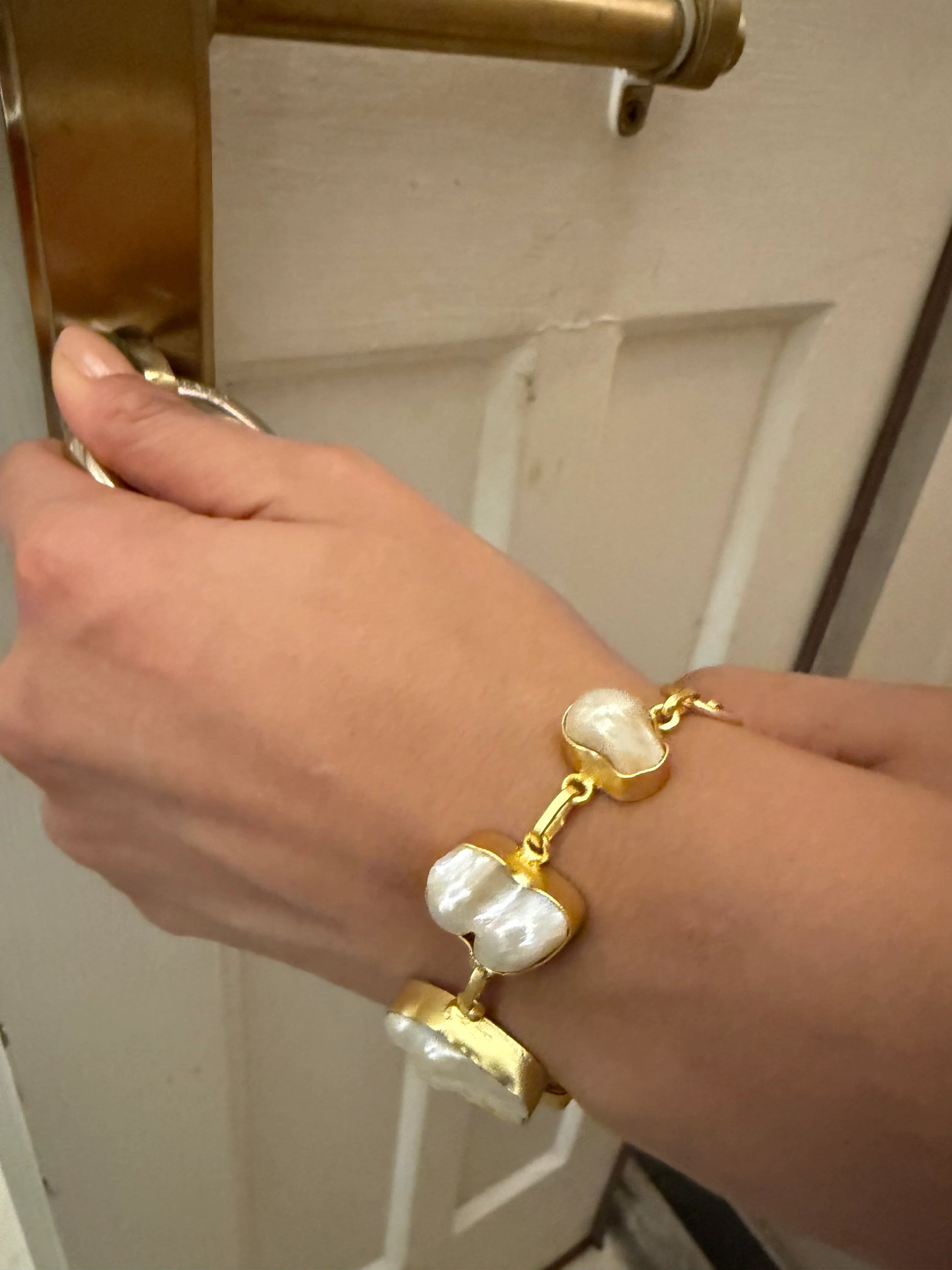 Stylish gold and pearl bracelet on wrist with minimal background highlighting jewelry details
