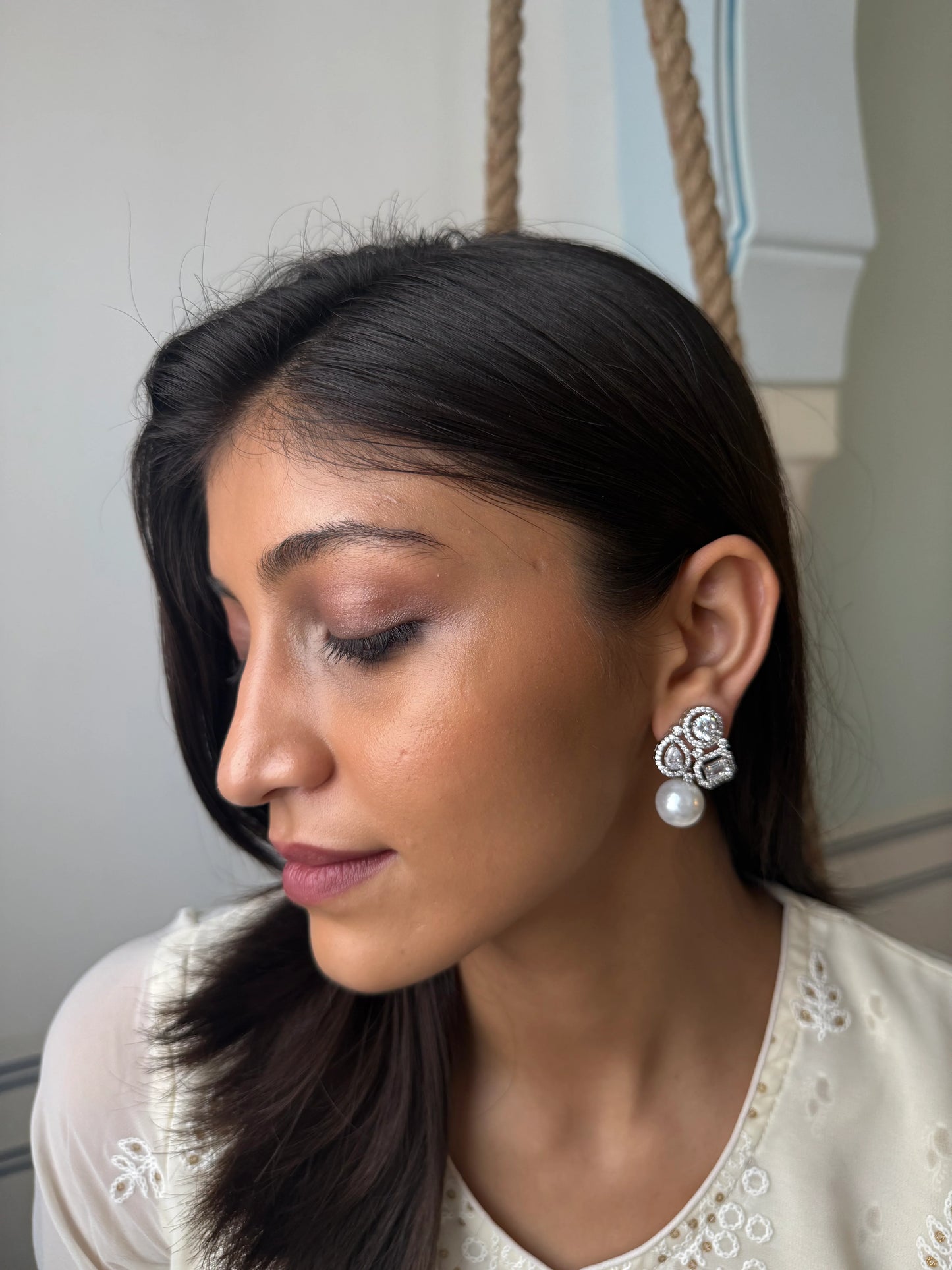 Minimalist fashion portrait of woman with straight hair wearing pearl floral earrings
