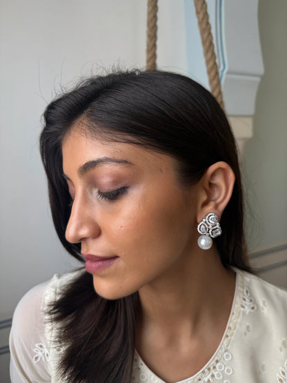 Minimalist fashion portrait of woman with straight hair wearing pearl floral earrings
