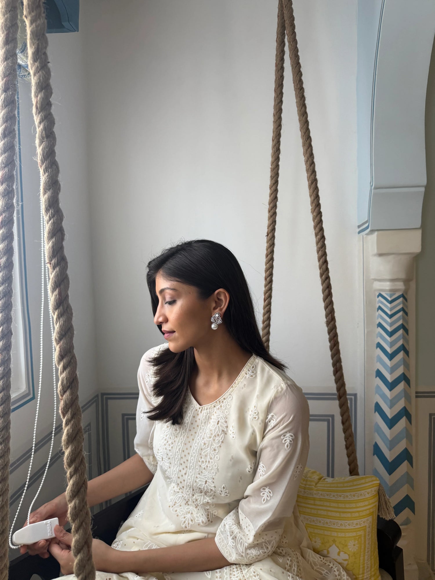 Close-up of female model wearing floral pearl earrings with soft neutral background
