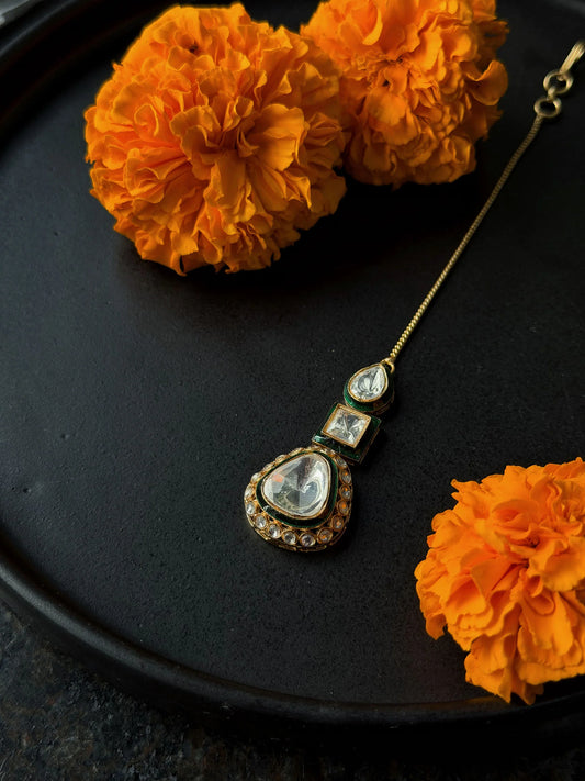 Elegant gold pendant necklace with kundan stones and green accents styled with marigold flowers
