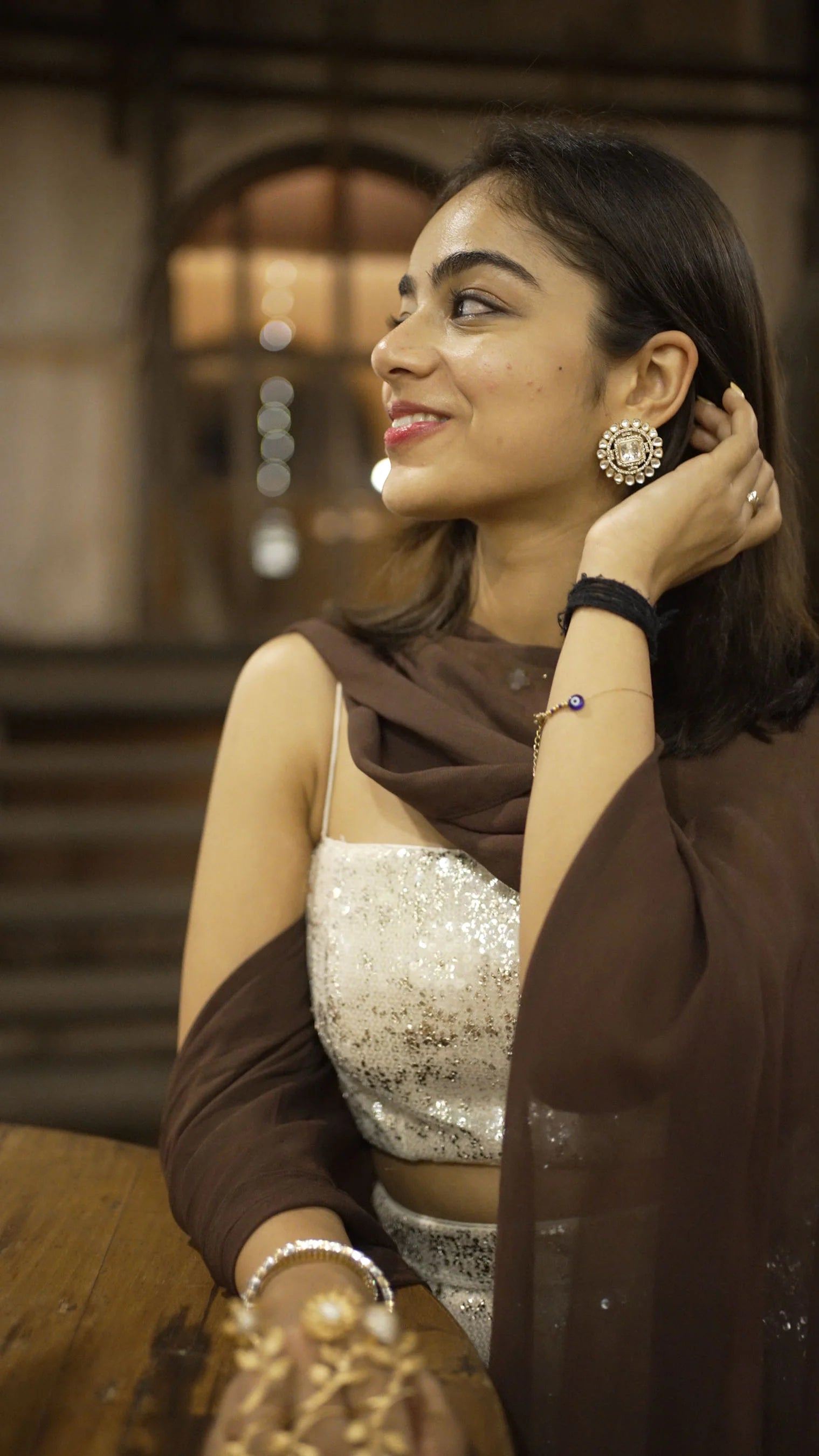 Cultural celebration setup with woman in red dress decorating home altar with flowers
