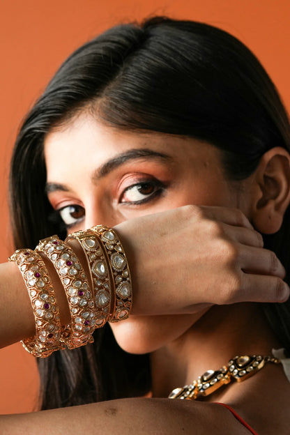 Luxury styling shot showcasing a woman in a richly detailed gold outfit with coordinated jewelry including a choker, earrings, and bracelets.
