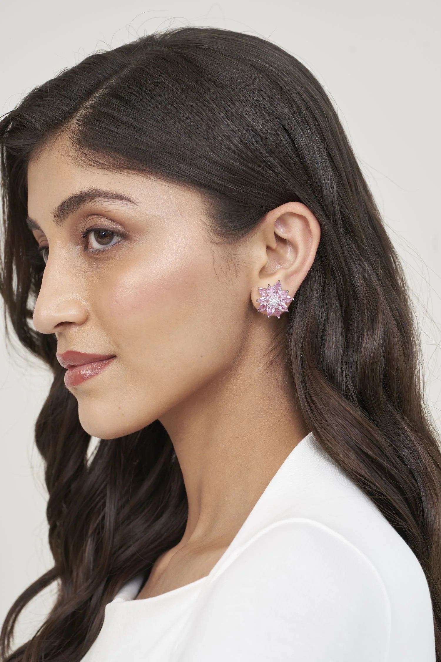 Sophisticated portrait detail showcasing a blush-toned gemstone earring with a dimensional cluster forming a star-like silhouette.
