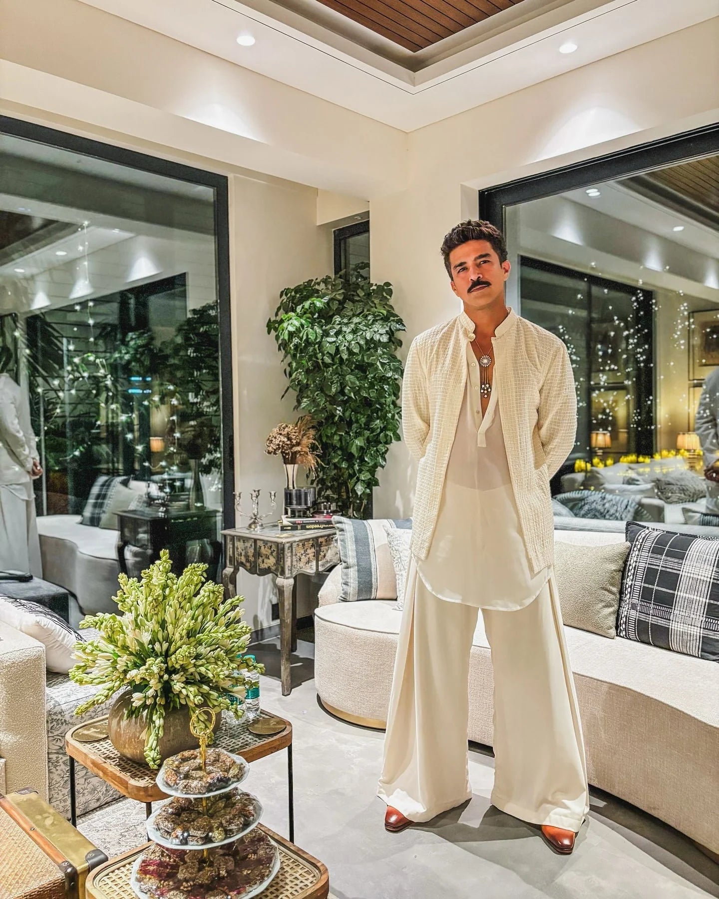Cozy luxury interior with a man relaxing on a sofa near large windows and decorative lighting
