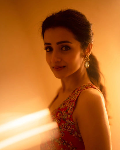 Close-up of a woman with soft glam makeup and ornate earrings in a red ethnic outfit with golden tones
