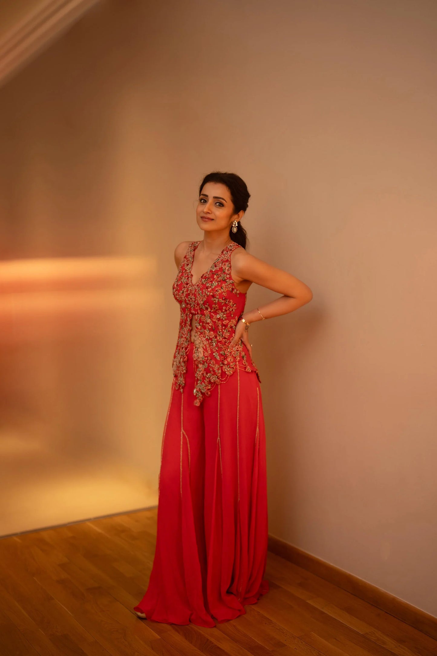 Indian ethnic fashion shot featuring a woman in a red outfit with detailed embroidery and jewelry
