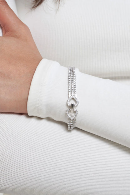 Fine jewelry bracelet featuring triple strands of pavé diamonds and a sculptural link centerpiece on a clean background.
