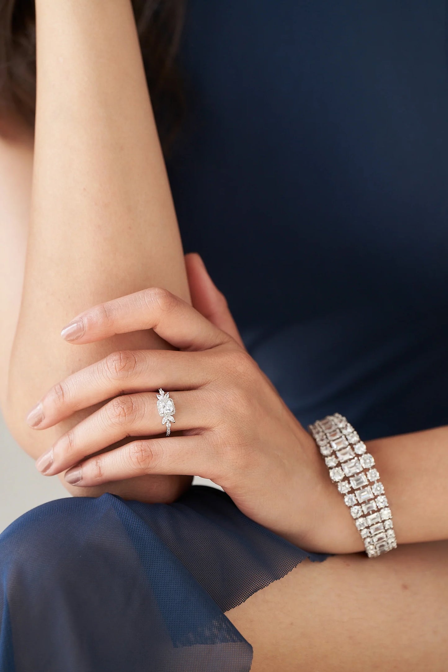 Delicate white gold ring showcasing a brilliant cushion-cut diamond with small marquise accents for a refined, nature-inspired design.
