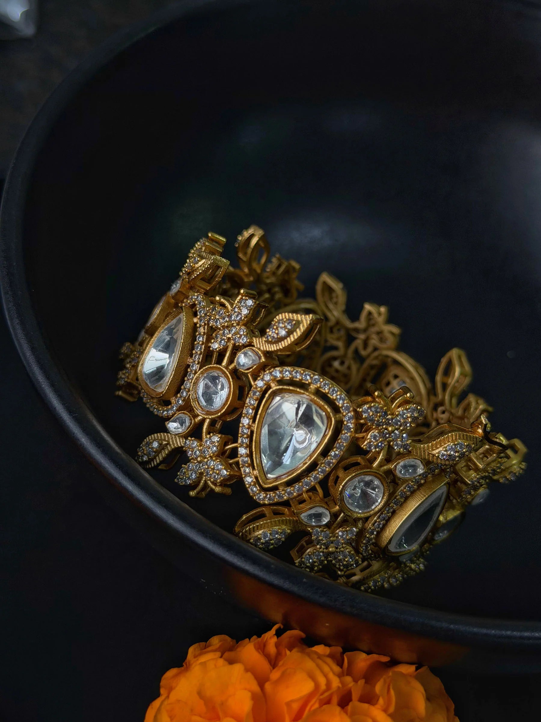 Luxury gold bracelet with kundan stones and intricate floral design on dark background
