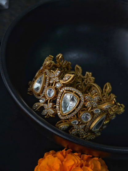 Luxury gold bracelet with kundan stones and intricate floral design on dark background
