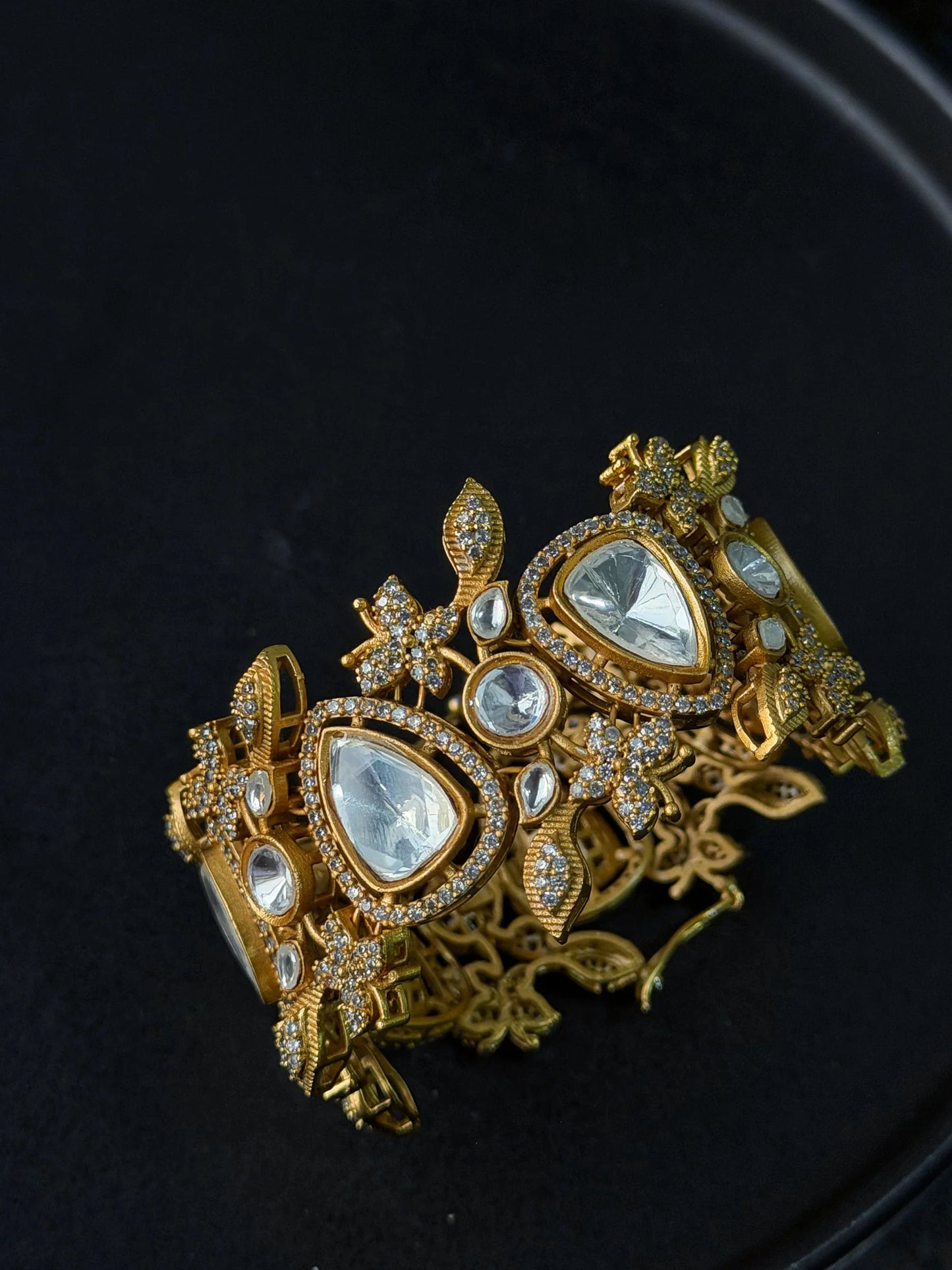 High-end gold bracelet with teardrop stones and intricate detailing in moody lighting

