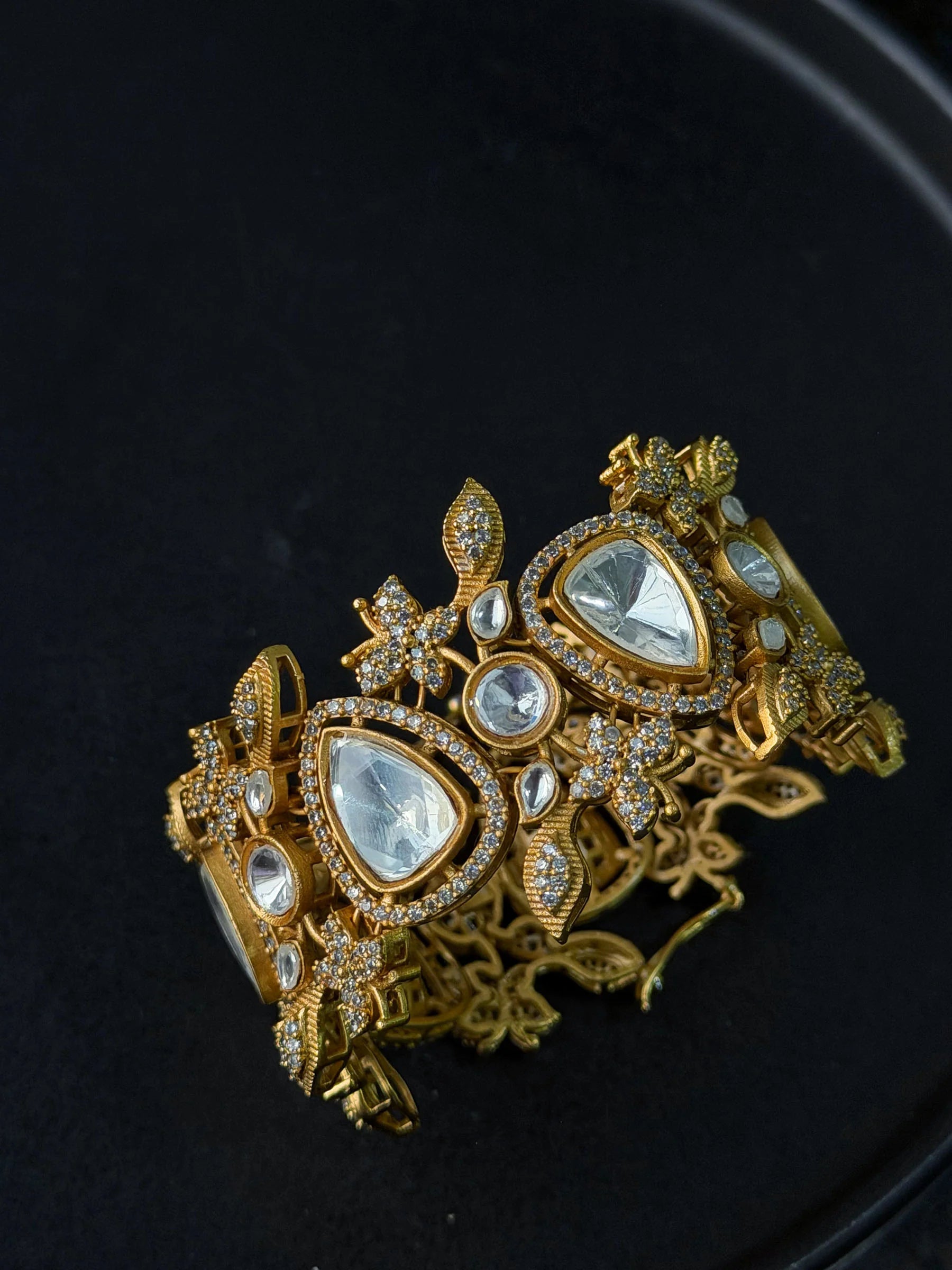 High-end gold bracelet with teardrop stones and intricate detailing in moody lighting
