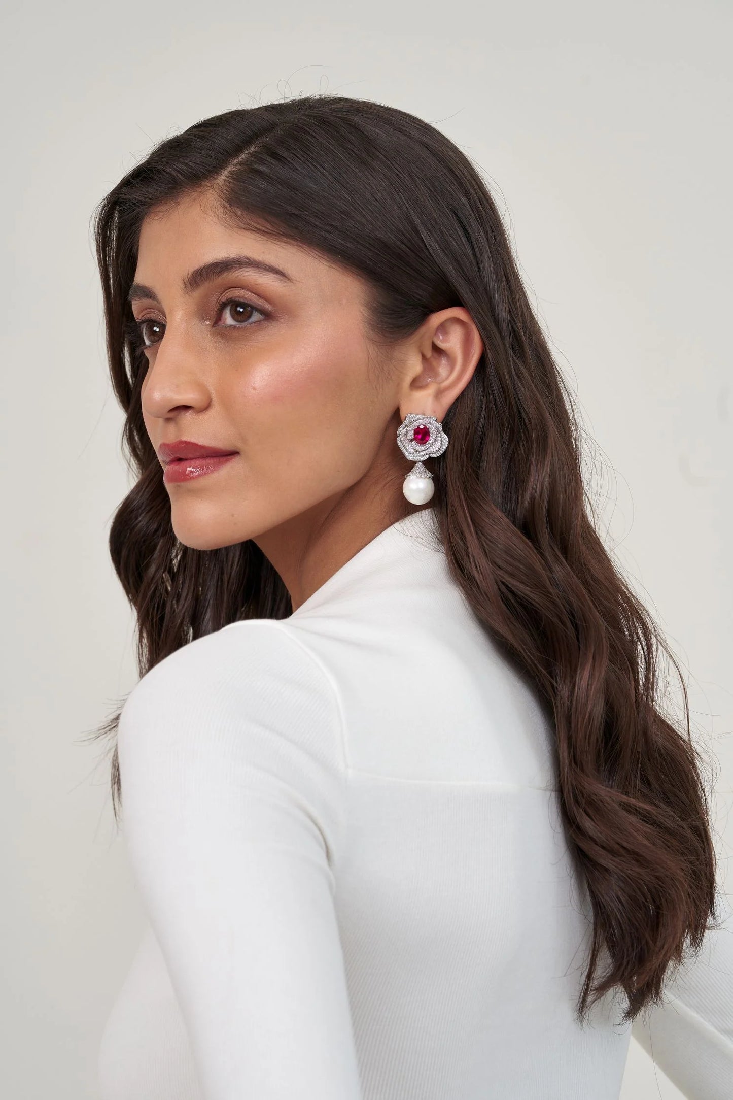Sophisticated beauty shot showcasing a gemstone and diamond flower earring finished with a luminous pearl drop.
