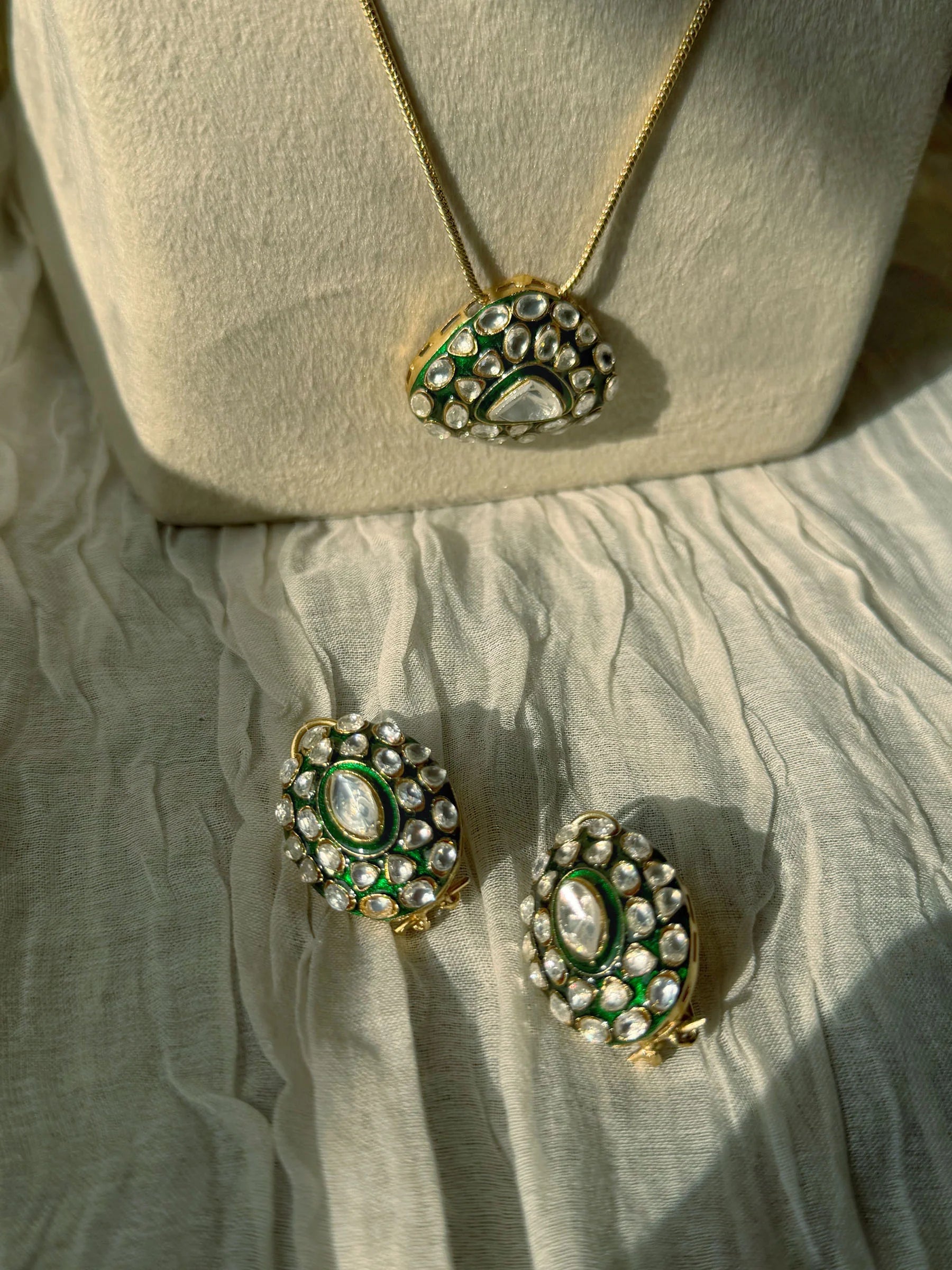 Elegant layered necklace with emerald pendant and matching kundan earrings display
