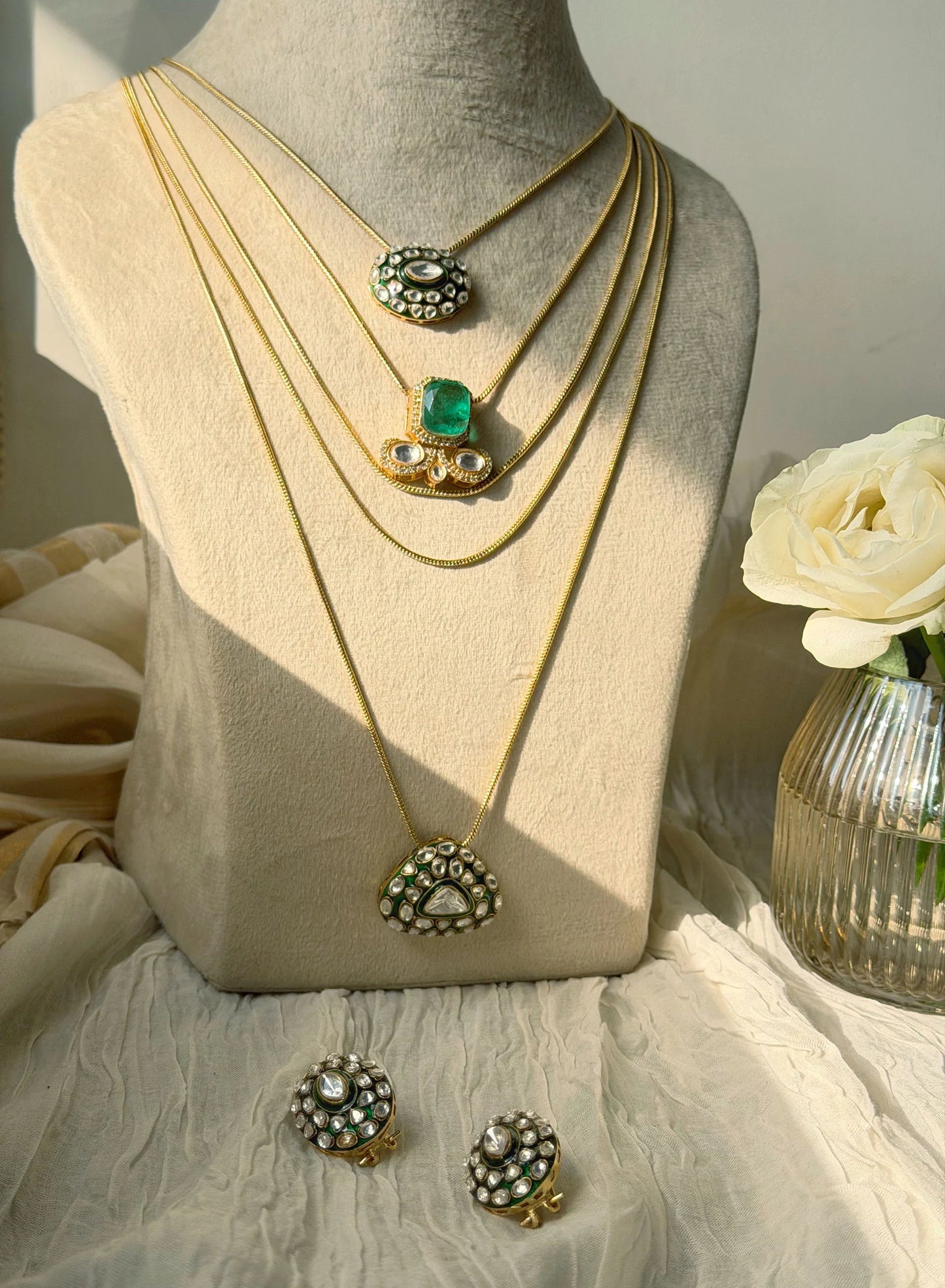Premium gold layered necklace set with green stone pendants in soft natural lighting
