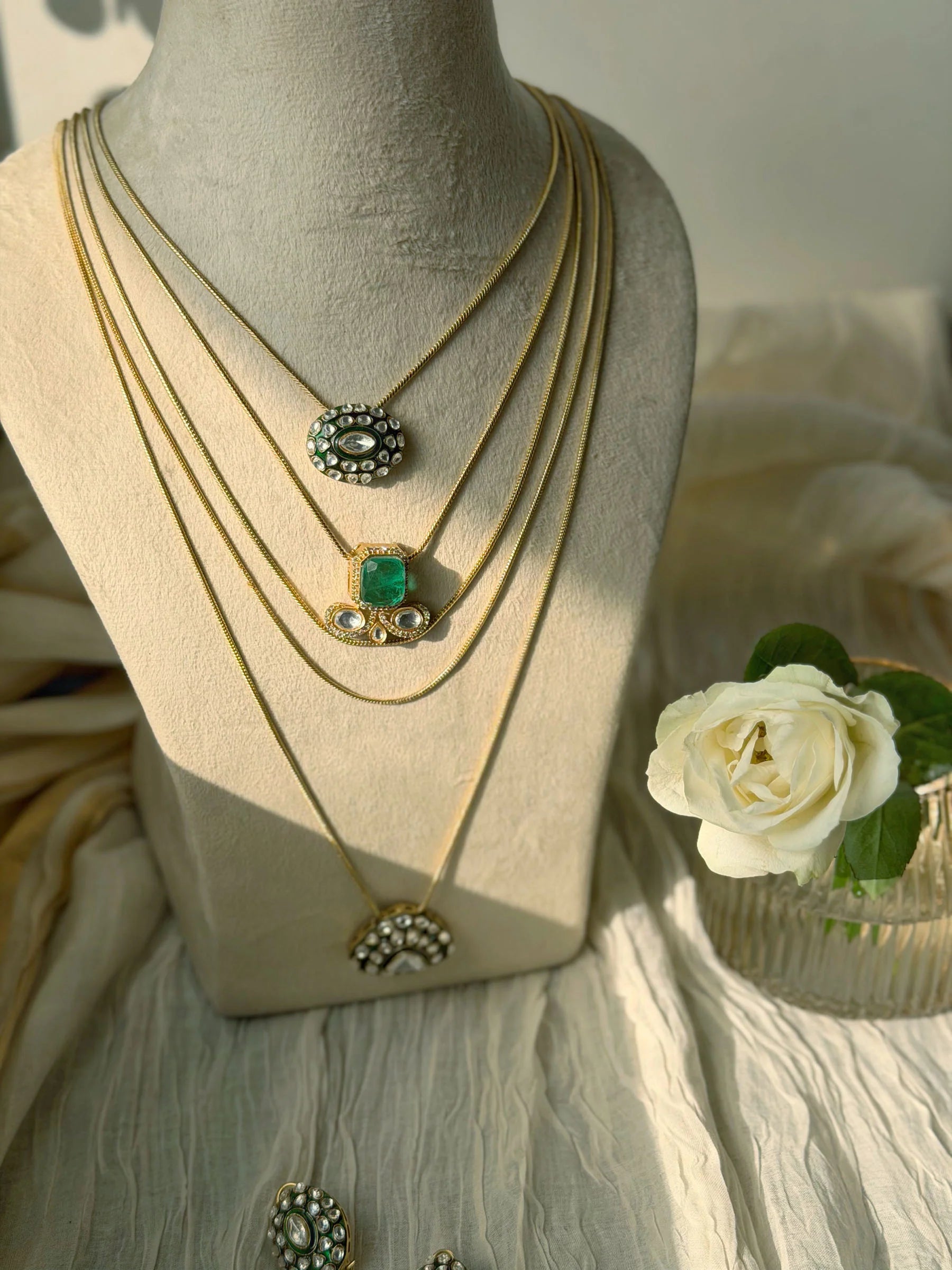 Traditional Indian jewelry with layered gold chains and emerald kundan pendants
