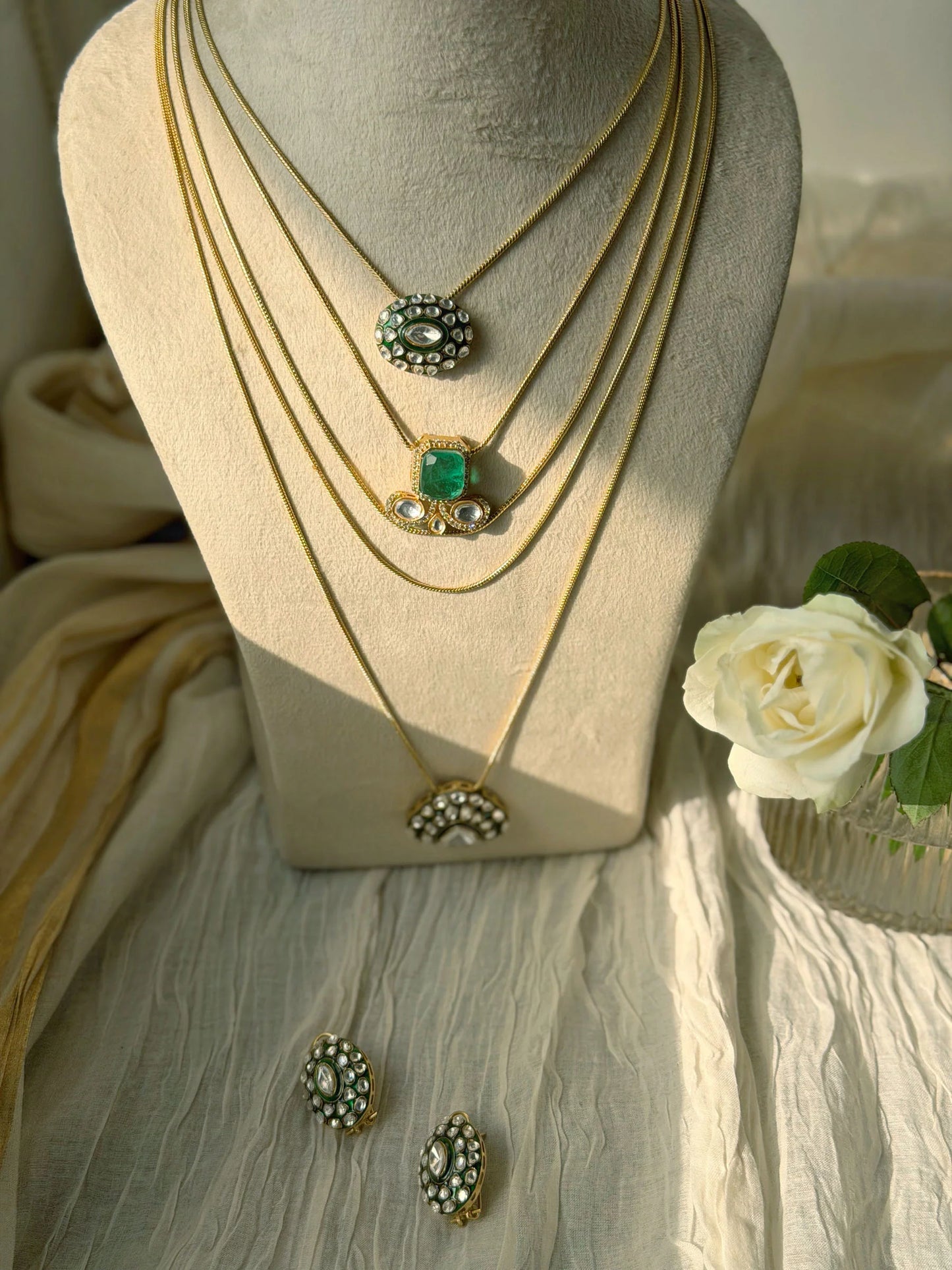 Designer layered necklace featuring green gemstone and intricate kundan work
