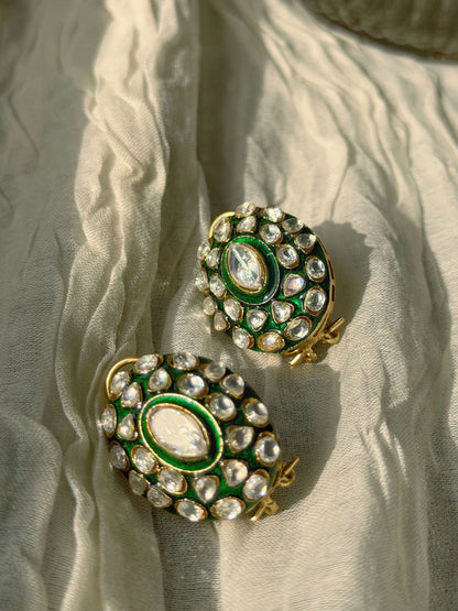 Close-up of layered gold chains with emerald centerpiece on fabric-draped bust

