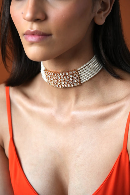 Sophisticated close-up of a woman showcasing a bold diamond choker while softly framing her neck with her hands.

