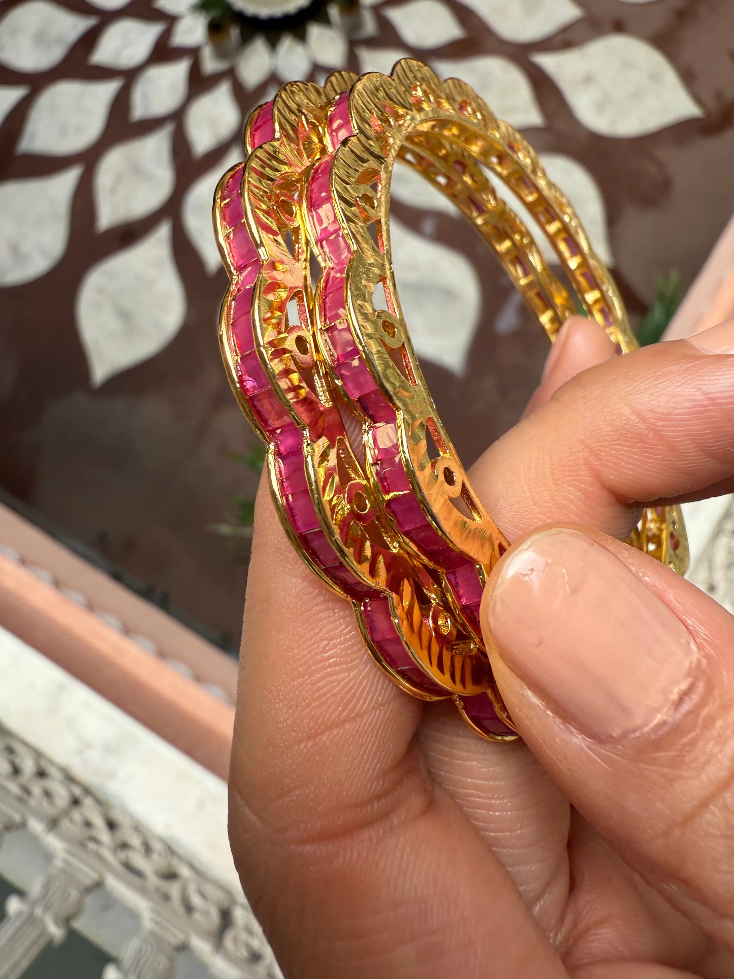 Woman smiling in red traditional attire arranging flowers near brass diya and garlands

