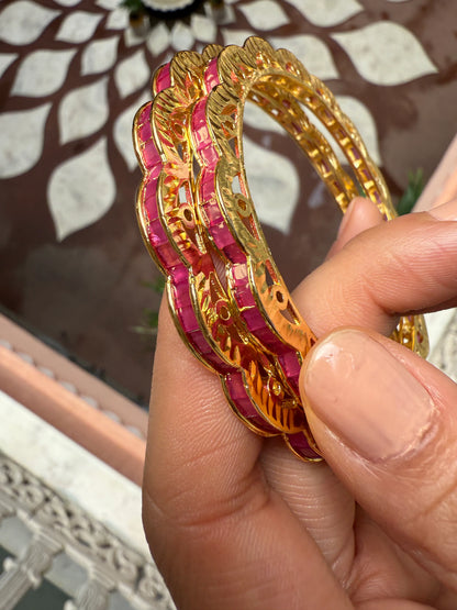 Woman smiling in red traditional attire arranging flowers near brass diya and garlands
