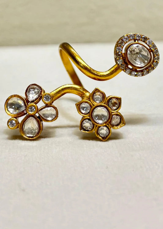 Stylish gold ring with floral shapes and embedded clear stones showcased on display surface
