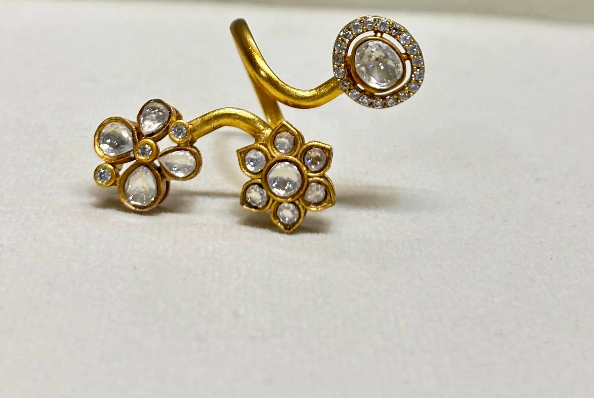 Elegant gold adjustable ring with flower motifs and clear gemstones in detailed close-up accents
