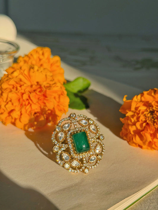 Luxury emerald ring with ornate gold setting and sparkling crystal accents on soft background
