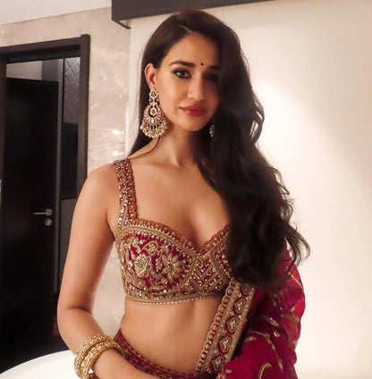 Detailed shot of a woman in festive attire with intricate gold embroidery, styled with chandelier earrings and a statement ring.

