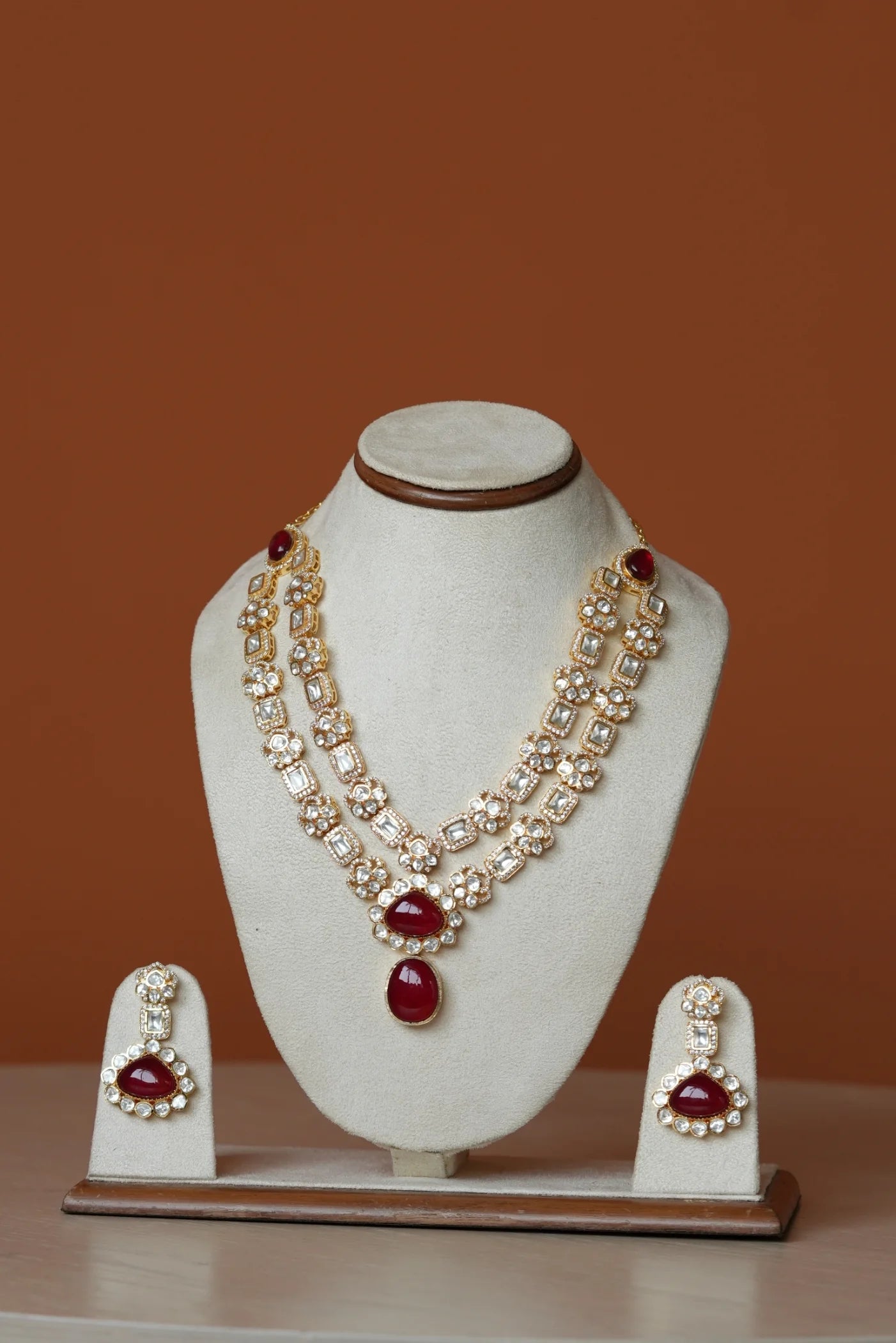 Two women posing together at an evening event, wearing a red outfit and a black embroidered saree with statement jewelry.
