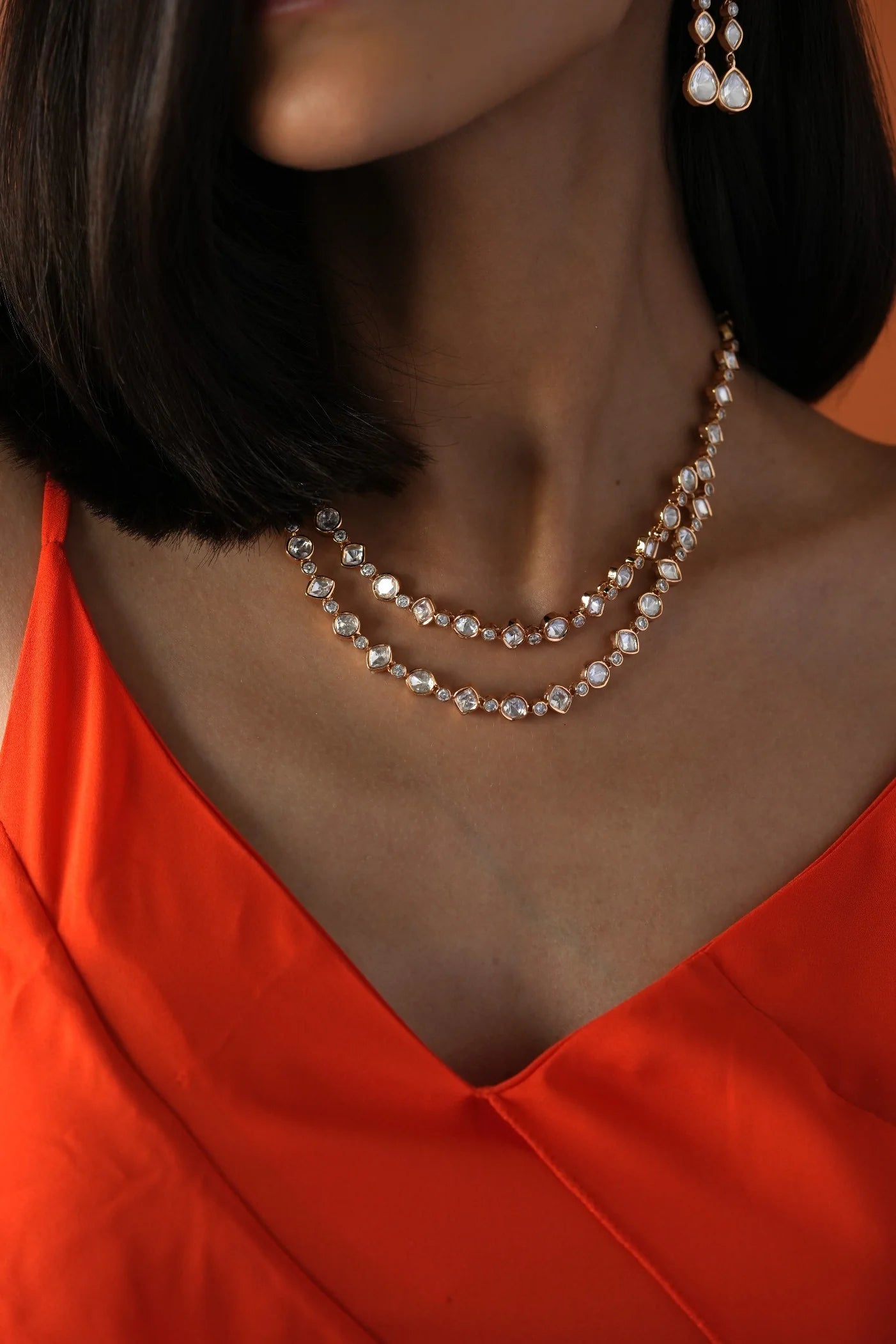 Luxury jewelry portrait capturing a woman in a minimal pose wearing intricate drop earrings and coordinated layered necklaces.

