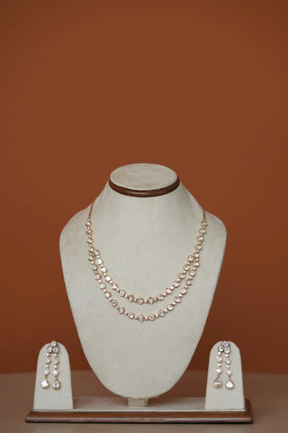 Detailed profile view focusing on sparkling drop earrings and layered necklaces styled against a soft, warm background.
