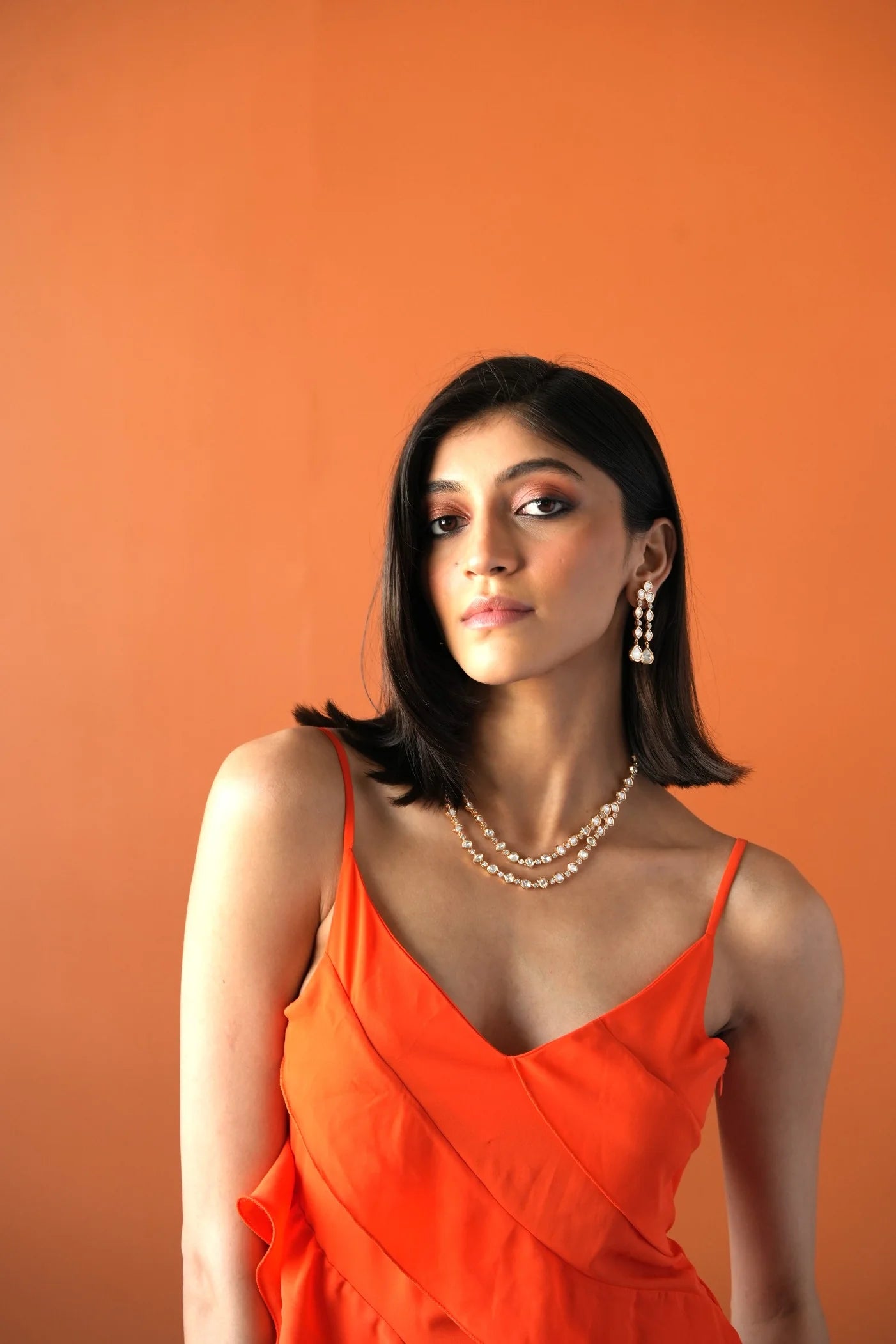 Sophisticated beauty shot showcasing a woman wearing statement chandelier earrings and stacked diamond necklaces.

