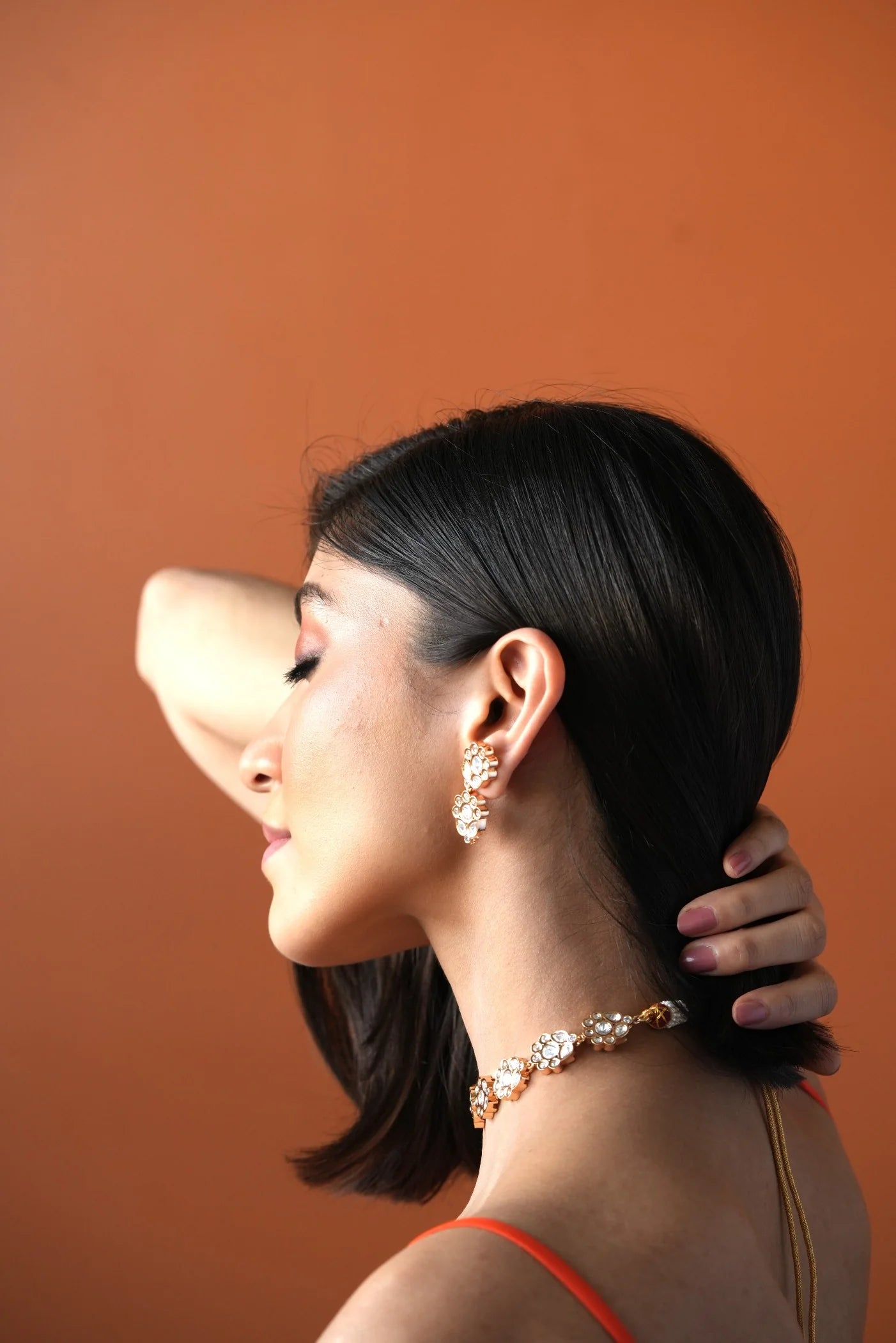 Fine jewelry close-up featuring elongated drop earrings with multiple stones paired with delicate layered diamond chains.
