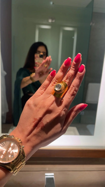 Luxury jewelry styling featuring stacked gold bangles and bold rings on hands against a classic car interior
