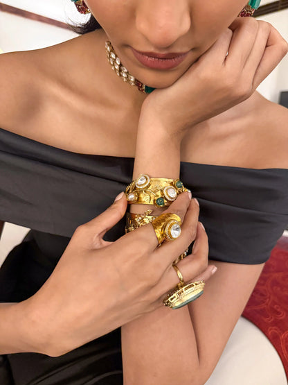 High-end fashion shot of hands decorated with heavy gold jewelry including bracelets and statement rings
