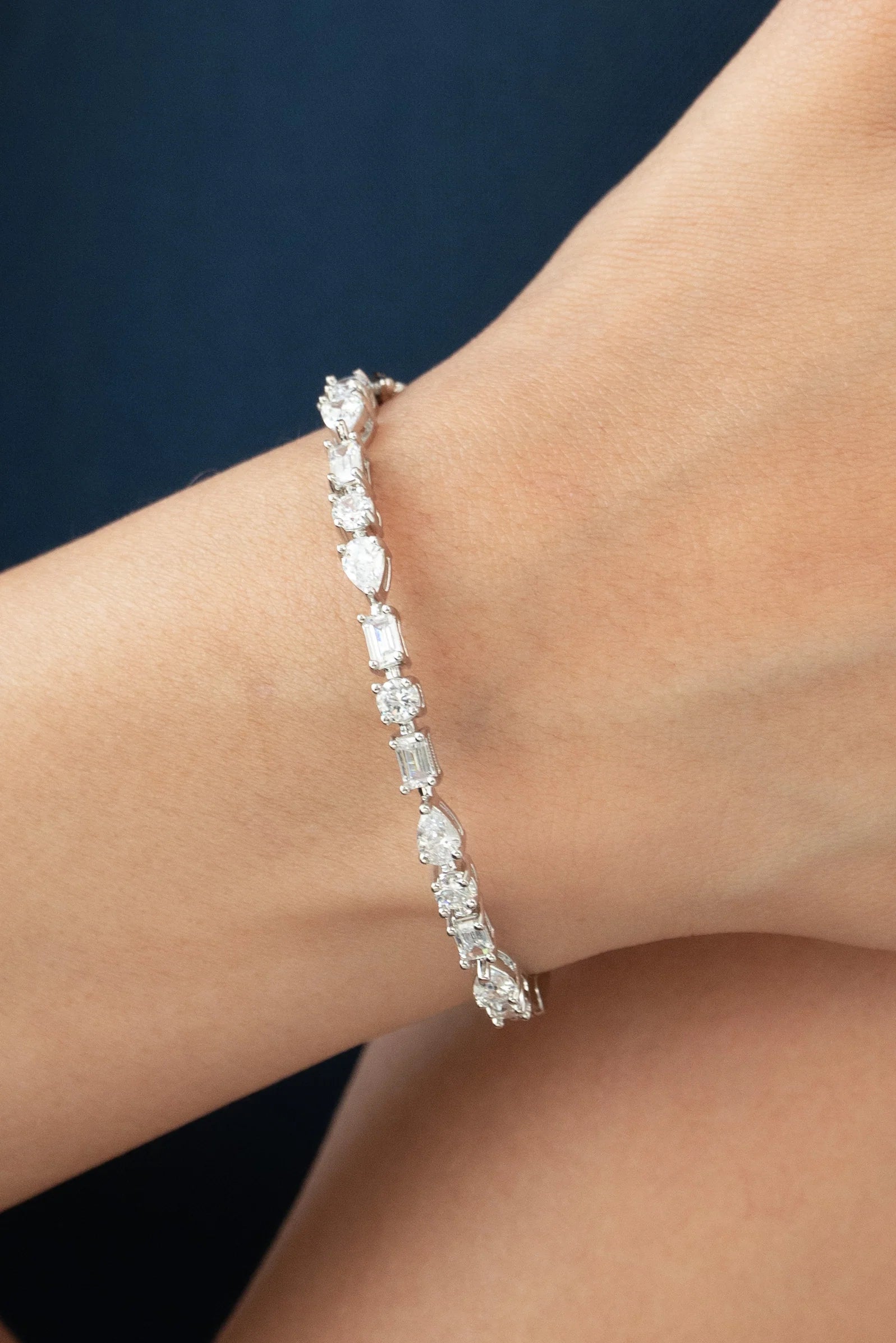 Delicate wrist bracelet featuring an eclectic mix of diamond cuts, including emerald, pear, and round stones set in a sleek white gold chain.
