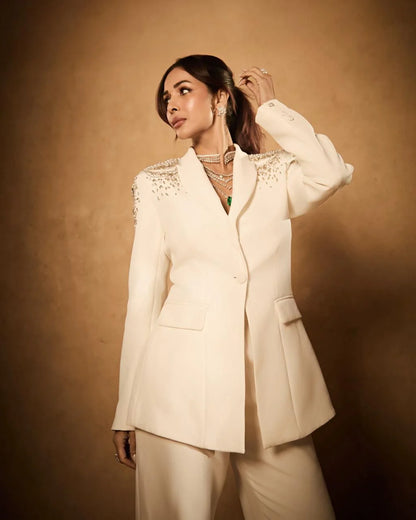 Luxury portrait of woman in cream suit adorned with sparkling shoulder details and layered necklaces
