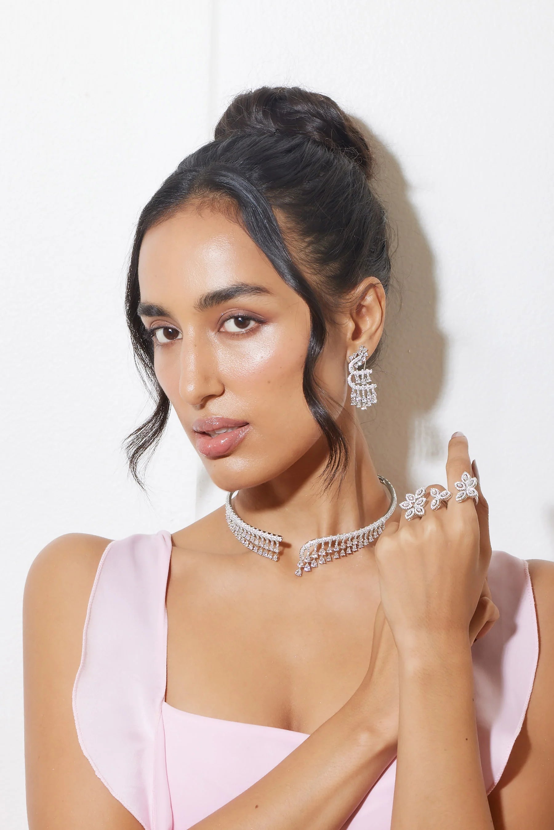 Glamorous model in ivory blazer paired with diamond choker and emerald pendant necklace

