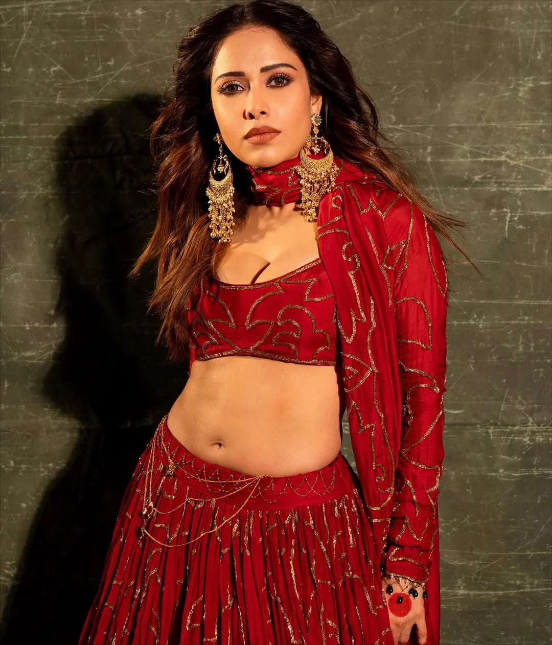 Indian festive outfit in red with detailed gold embellishments and accessories
