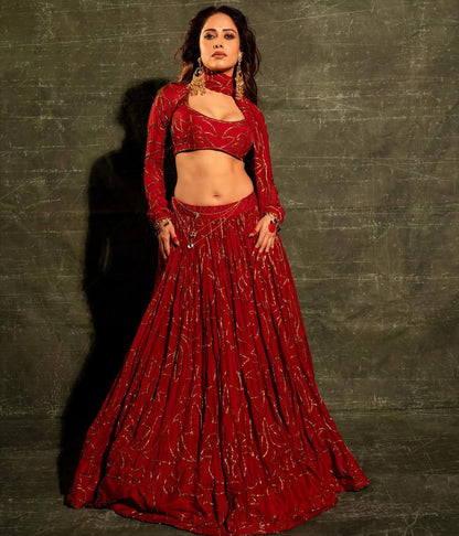 Fashion portrait of woman in red lehenga with intricate gold detailing and bold styling
